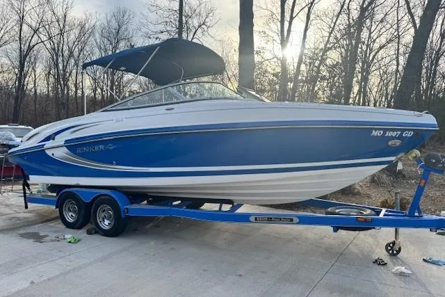 Slide: The Image of 2013 Rinker 246 Captiva Bowrider on trailer, blue and white, parked outdoors. - 6