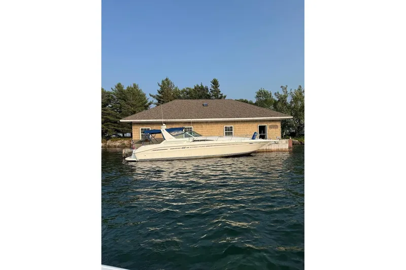 The Image of 1991 Sea Ray 400 Express Cruiser docked by a lakeside boathouse. - 1