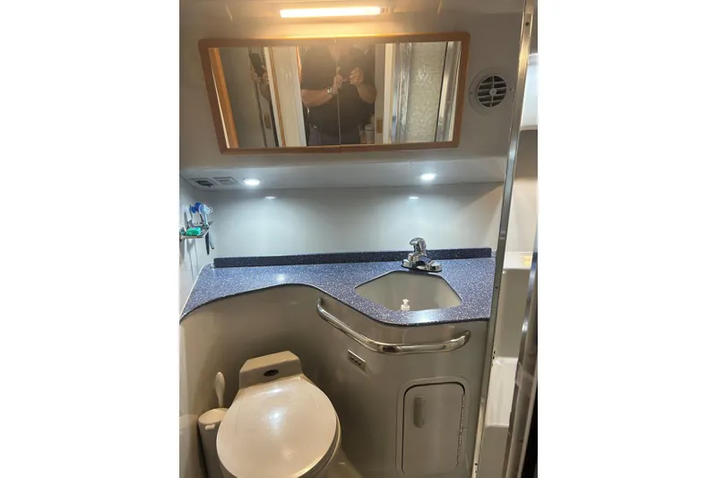 Slide: The Image of Bathroom interior of 1991 Sea Ray 400 Express Cruiser with sink, mirror, and toilet. - 11