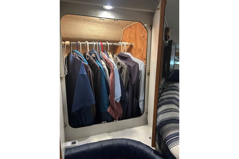 Slide: The Image of Closet with clothes inside a 1991 Sea Ray 400 Express Cruiser boat cabin. - 5