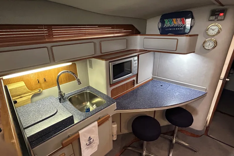 Slide: The Image of 1991 Sea Ray 400 Express Cruiser kitchen with sink, microwave, and bar stools. - 9