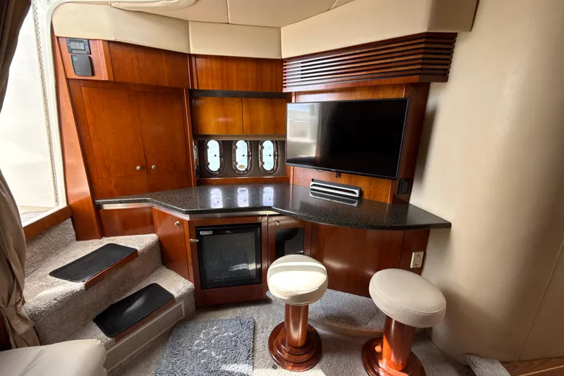 Slide: The Image of Luxurious 2006 Cruisers Yachts 420 Express interior with TV, bar stools, and wooden cabinetry. - 22