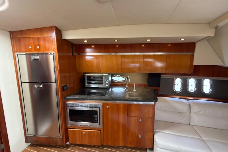 Slide: The Image of Luxurious 2006 Cruisers Yachts 420 Express interior kitchen with wood cabinetry and modern appliances. - 24