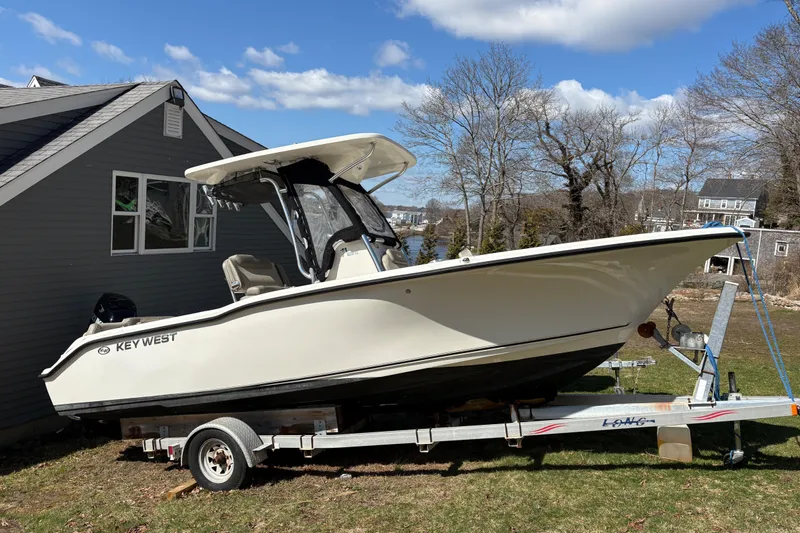 The Image of 2023 Key West 239 FS boat on trailer beside house, under clear blue sky. - 0