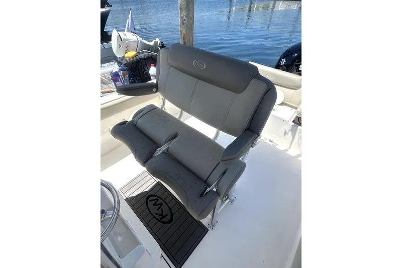 Slide: The Image of 2023 Key West 239 FS boat seat with gray upholstery and armrests, docked by water. - 18
