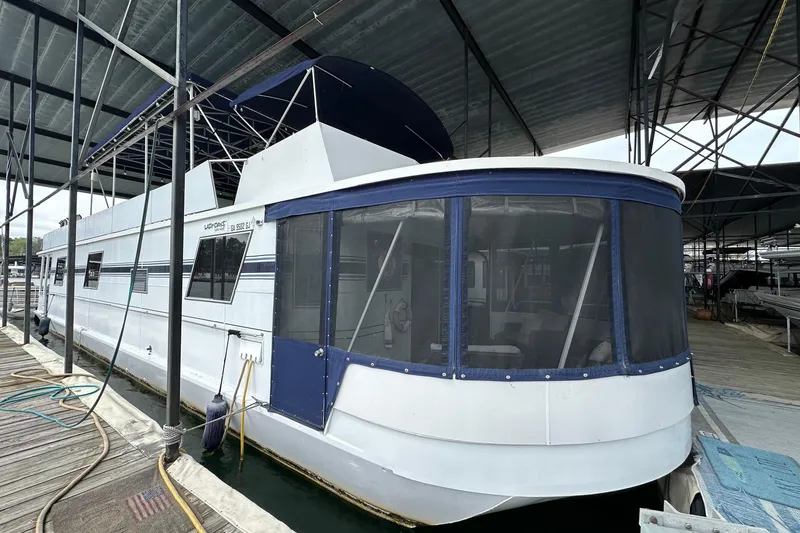The Image of Houseboat docked under shelter, Lazy Days 15x64 model, 1996, with blue accents. - 0
