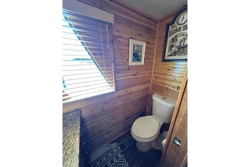 Slide: The Image of Cozy wooden bathroom with toilet, window blinds, and nautical-themed decor in a 1996 Lazy Days model. - 11