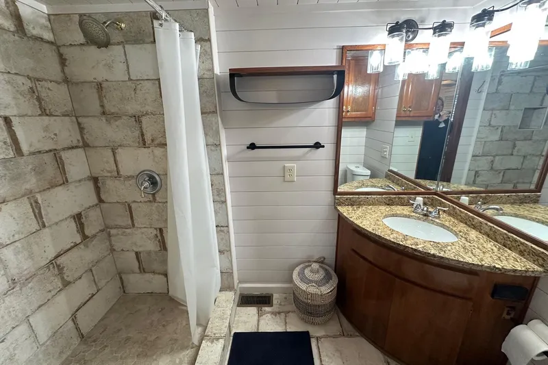 Slide: The Image of Bathroom with stone shower, granite countertop, and wooden cabinetry in a 1996 Lazy Days 15x64 model. - 14