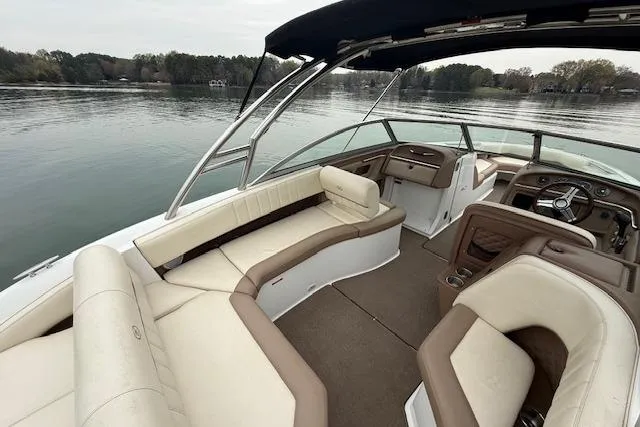 Slide: The Image of 2010 Cobalt 276 boat interior with beige seating, steering wheel, and lake view. - 11