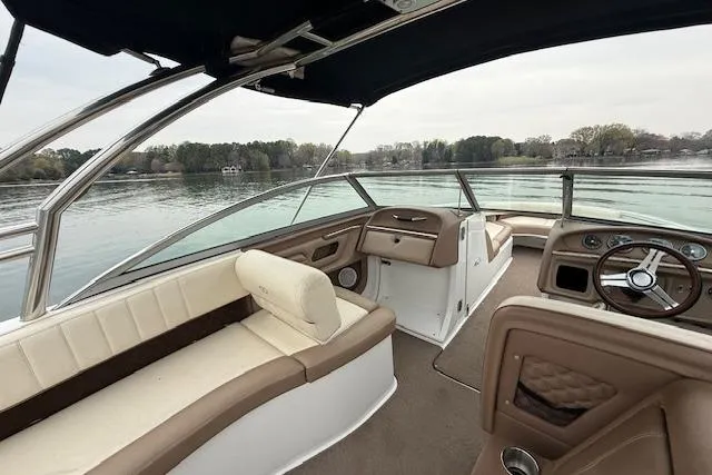 Slide: The Image of 2010 Cobalt 276 boat interior with beige seating, steering wheel, and lake view. - 13