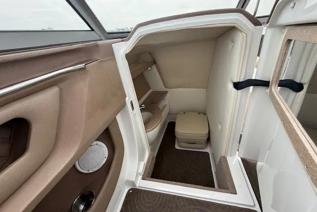 Slide: The Image of Interior of a 2010 Cobalt 276 boat featuring a compact bathroom with beige accents. - 16