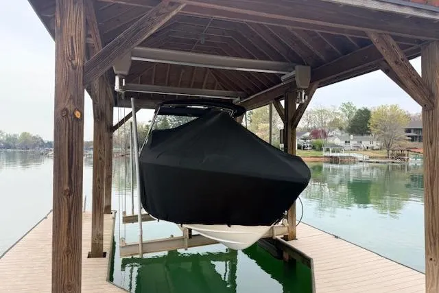 Slide: The Image of Covered 2010 Cobalt 276 boat on a wooden dock lift by a serene lake. - 3
