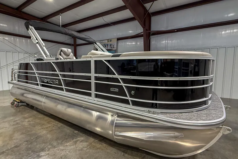 Slide: The Image of 2025 Trifecta 22UL LE pontoon boat in a showroom, featuring sleek black design. - 7