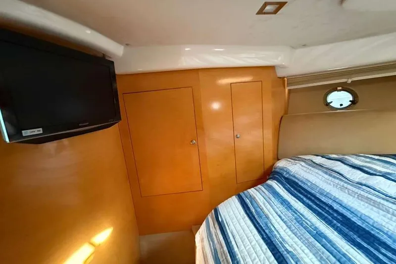 Slide: The Image of Interior of 2009 Cranchi Mediterranee 43 yacht with TV, wooden cabinets, and striped bedding. - 18