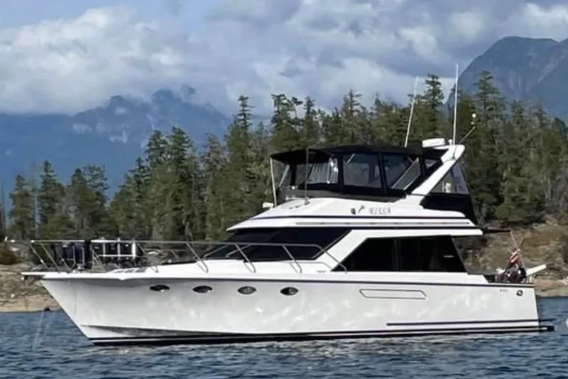 The Image of 1990 Ocean Alexander 420 Sport Sedan yacht cruising near forested shoreline. - 1