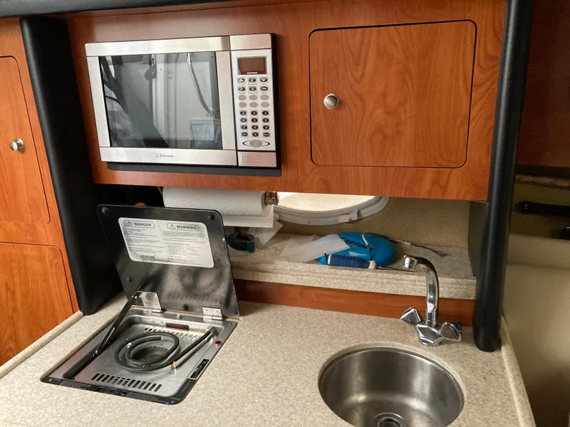 Slide: The Image of 2007 Rinker 280 Express Cruiser kitchenette with microwave and sink. - 45