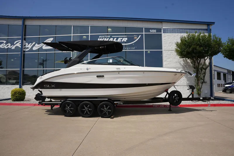 Slide: The Image of 2025 Sea Ray SLX 260 Surf boat in front of a showroom. - 0