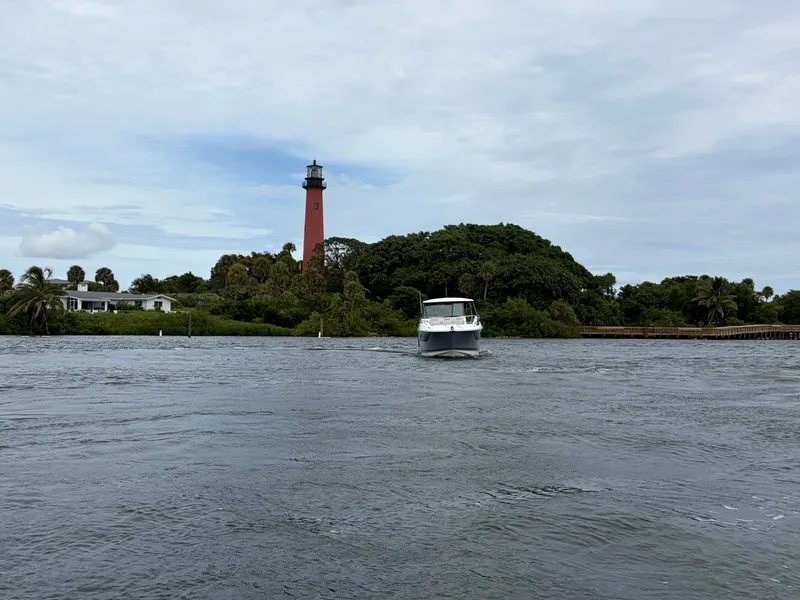 Slide: The Image of A Sea Ray Sundancer 320 Outboard boat on a river, with a lighthouse in the background. - 13