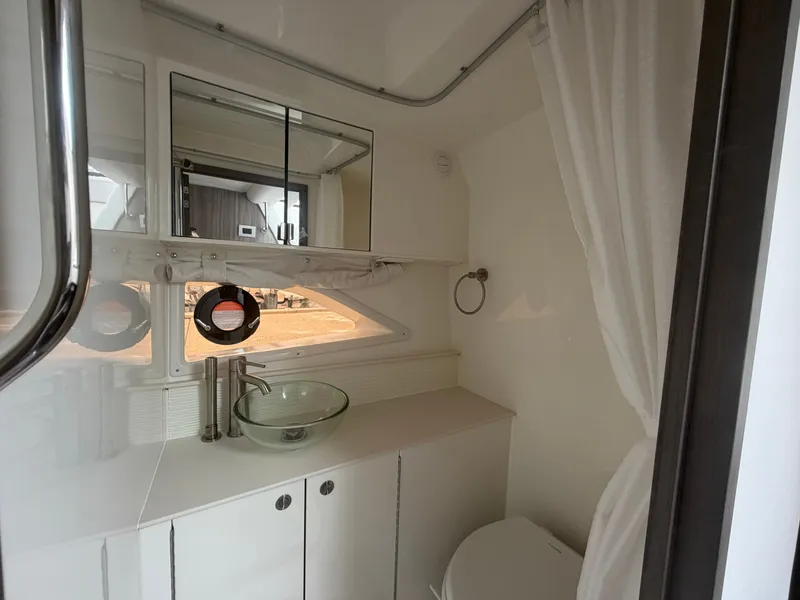 Slide: The Image of The image shows a modern boat bathroom with a glass sink and white cabinets. - 30