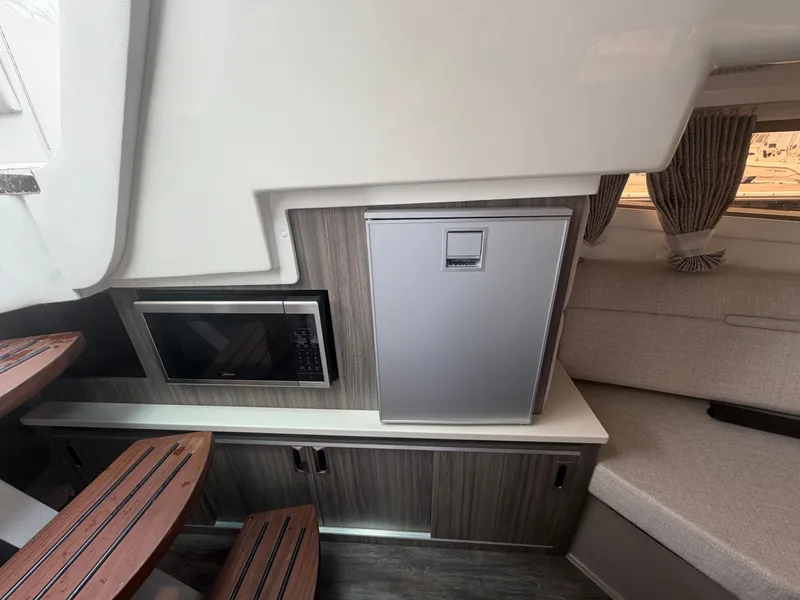 Slide: The Image of Interior of a Sea Ray Sundancer 320 Outboard with microwave, refrigerator, and seating area. - 32