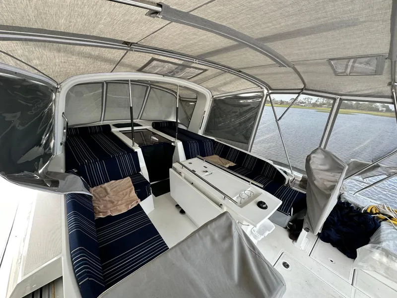 Slide: The Image of 2023 Beneteau Oceanis 46.1 yacht cockpit with striped seating and canopy, docked by the water. - 13