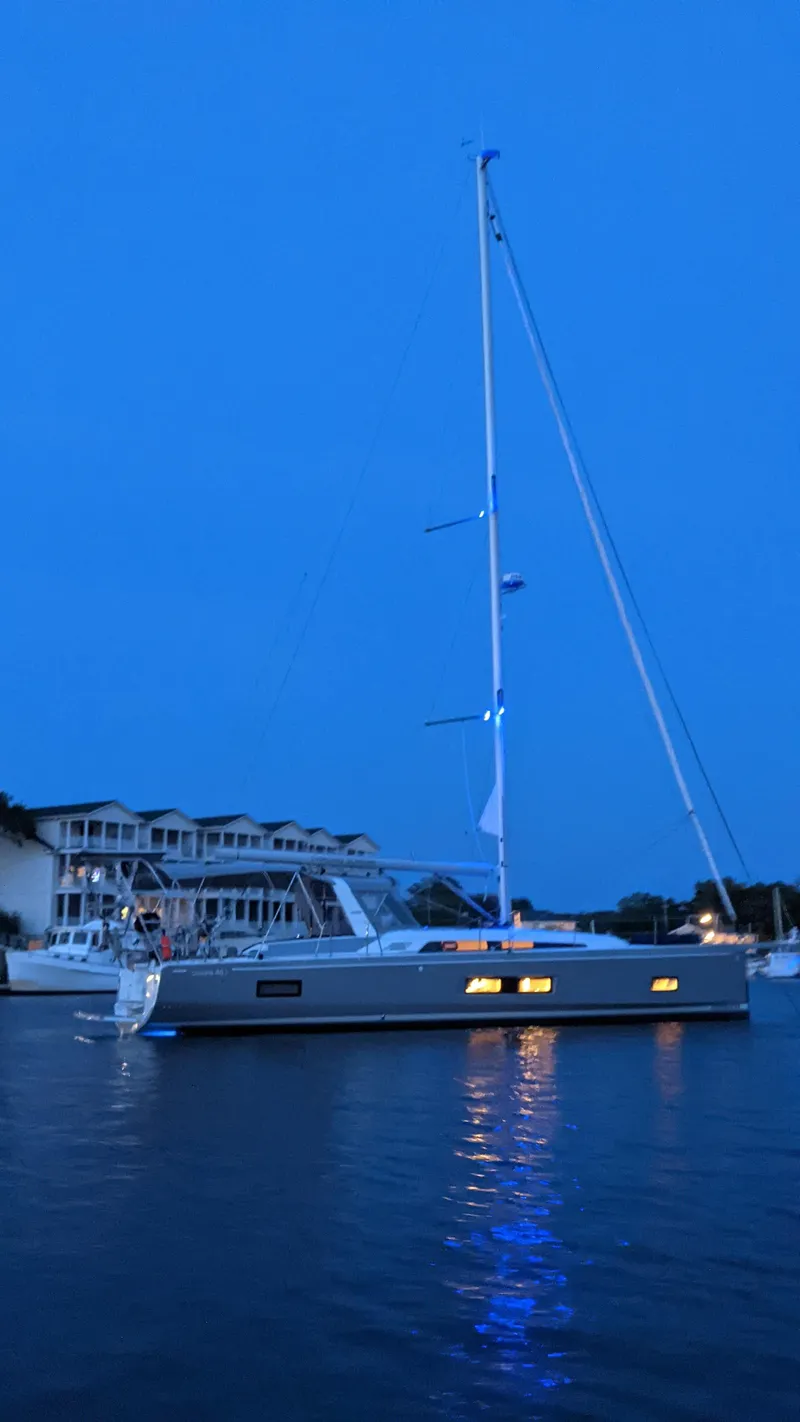 Slide: The Image of 2023 Beneteau Oceanis 46.1 sailboat illuminated at dusk on calm waters. - 33
