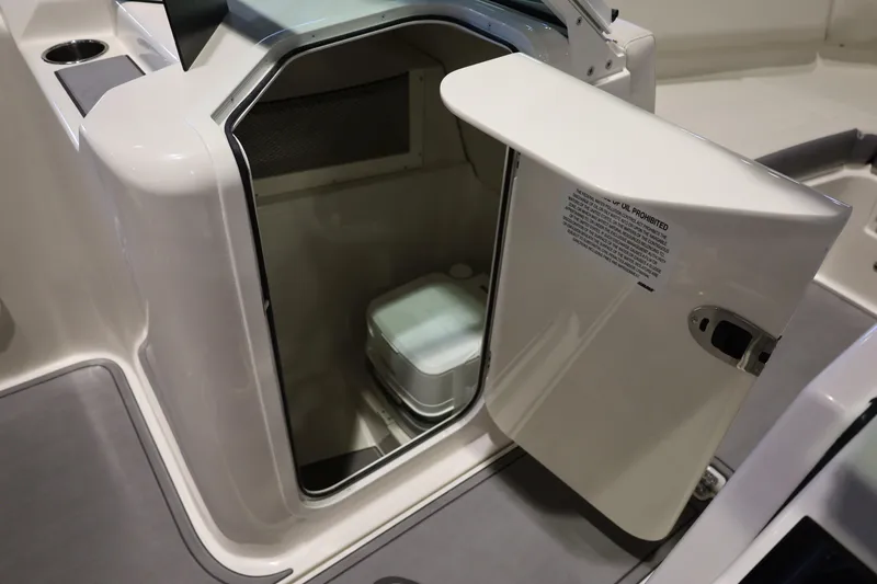 Slide: The Image of Open storage compartment on 2026 Sailfish 236 DC boat, featuring a portable toilet. - 25