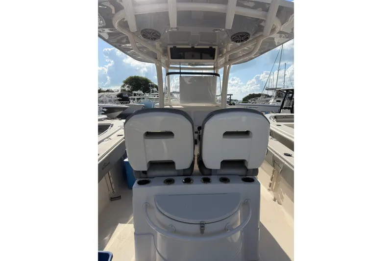 Slide: The Image of 2023 Sea Chaser 27 HFC CC boat interior with seating and console, docked under sunny skies. - 7