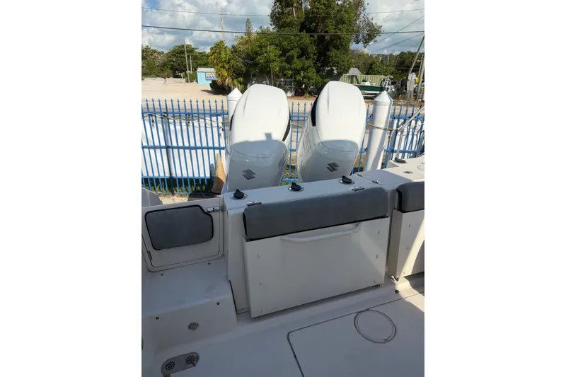 Slide: The Image of 2023 Sea Chaser 27 HFC CC boat with dual outboard motors, docked near a blue fence. - 8