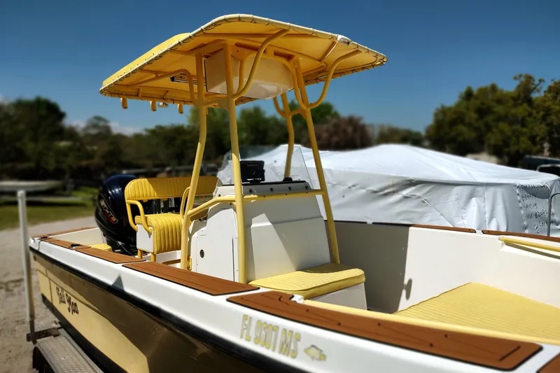 Slide: The Image of 2004 Angler 204 Center Console boat with yellow canopy and seating, parked outdoors. - 4