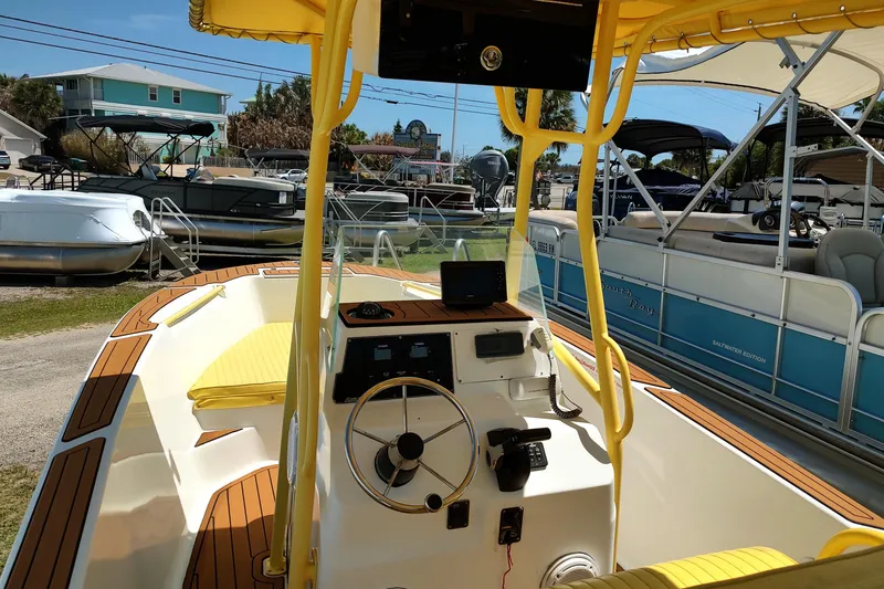 Slide: The Image of 2004 Angler 204 Center Console boat with yellow accents, docked near other boats. - 8