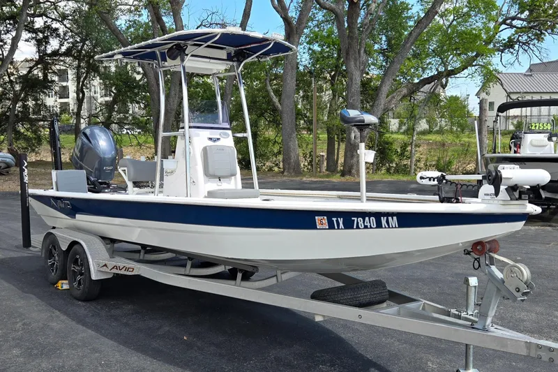 The Image of 2021 Avid 23 FS boat on trailer, parked outdoors with trees in background. - 1