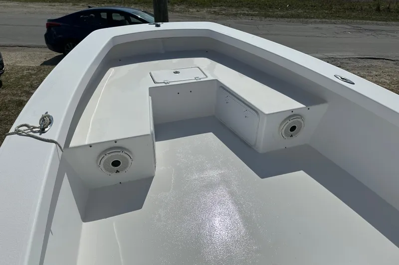 Slide: The Image of 2018 Intruder 23 boat interior with storage compartments and speakers, parked near a road. - 4