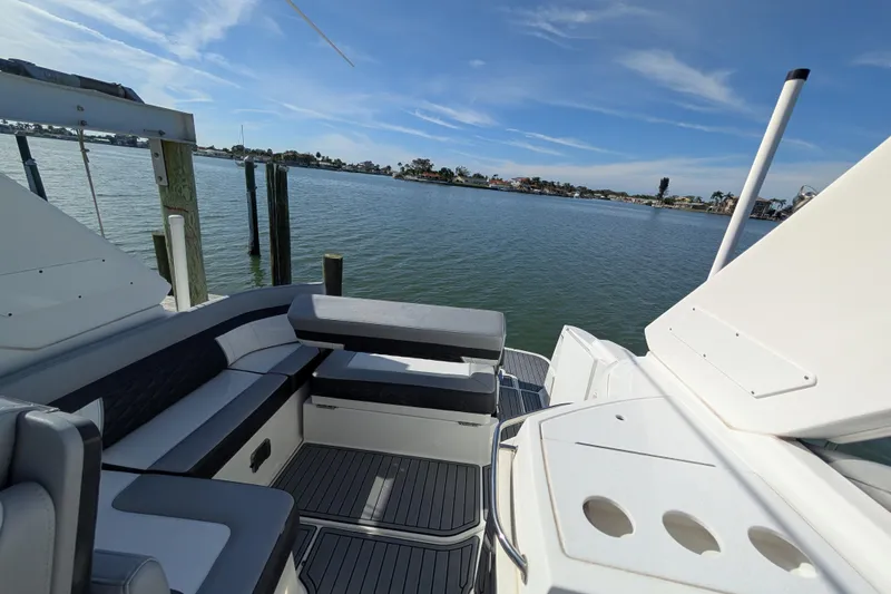 Slide: The Image of 2022 Monterey 295SS Super Sport boat interior with seating, docked by calm waters. - 12