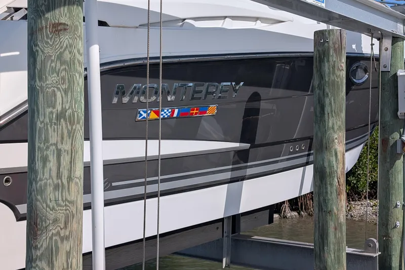 Slide: The Image of 2022 Monterey 295SS Super Sport boat docked, showcasing sleek design and nautical flags. - 3