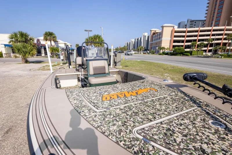 Slide: The Image of 2025 Mako 18 Pro Skiff Backwater Edition boat with camouflage deck, parked near a road. - 12