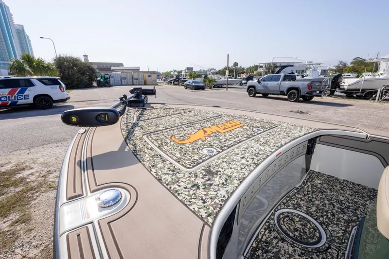 Slide: The Image of 2025 Mako 18 Pro Skiff Backwater Edition with camo design in a marina parking area. - 16