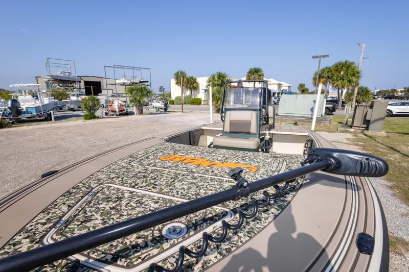 Slide: The Image of 2025 Mako 18 Pro Skiff Backwater Edition boat with camouflage deck, parked outdoors. - 17