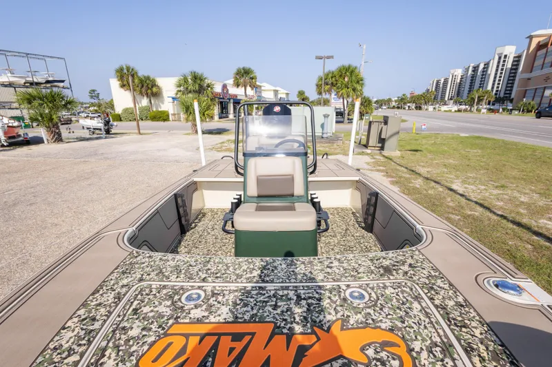 Slide: The Image of 2025 Mako 18 Pro Skiff Backwater Edition boat with camouflage deck, parked outdoors. - 24