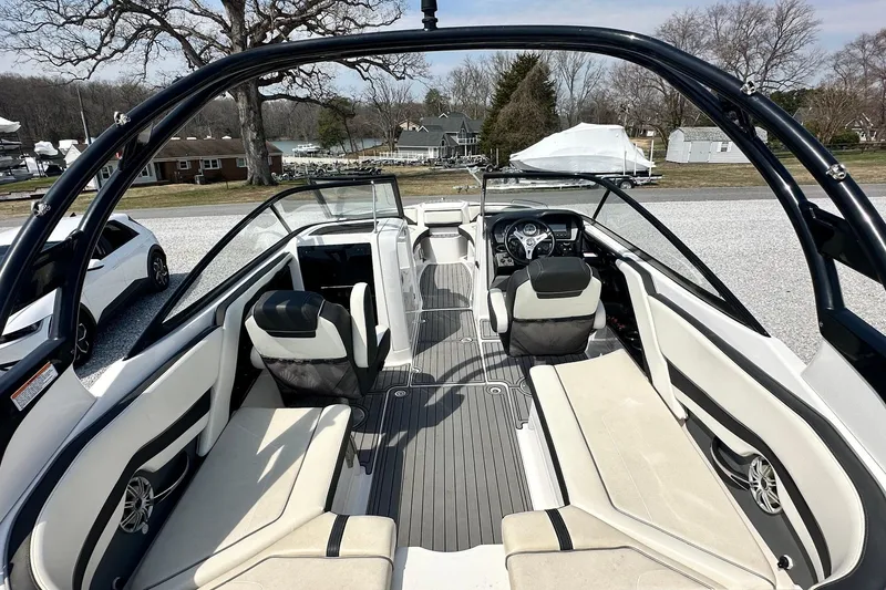 Slide: The Image of 2016 Yamaha 242 Limited S boat interior with seating and steering wheel, parked outdoors. - 16
