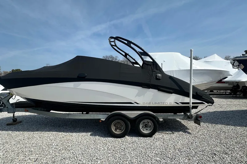 Slide: The Image of 2016 Yamaha 242 Limited S boat on trailer, covered, parked on gravel lot. - 2