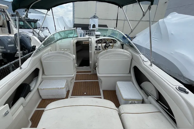 Slide: The Image of 2002 Sea Ray 225 Weekender boat interior with white seating and wooden flooring. - 1