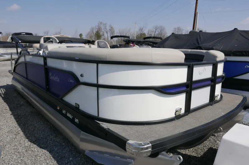 Slide: The Image of 2023 Barletta Cabrio 22UC pontoon boat displayed outdoors on gravel. - 2
