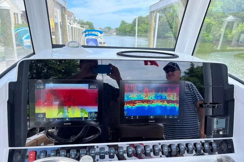 Slide: The Image of 2022 Sea Hunt Gamefish 30 dashboard with Garmin displays and scenic waterway view. - 7