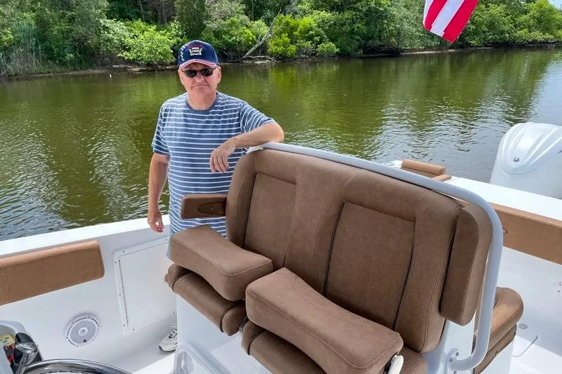 Slide: The Image of Man on 2022 Sea Hunt Gamefish 30 boat, standing by brown seating, near lush riverbank. - 8