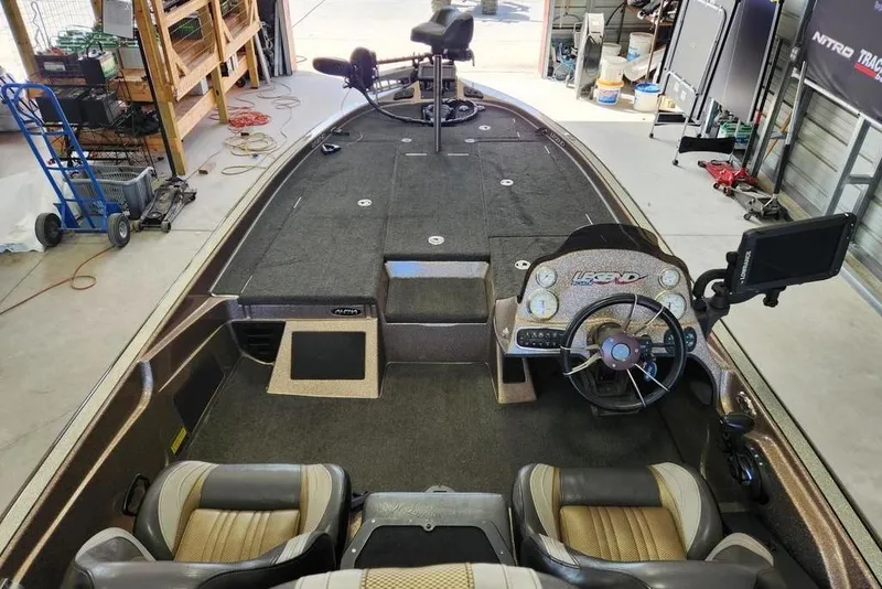 Slide: The Image of 2014 Legend 199 Alpha DC boat interior with steering wheel and seating in a garage. - 5