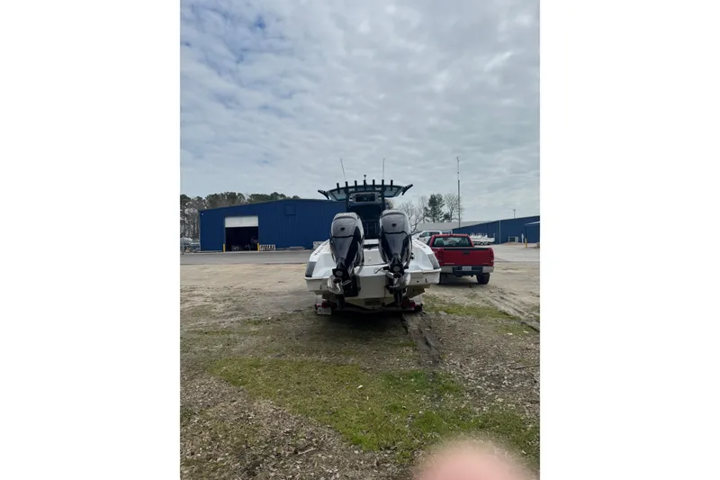 Slide: The Image of 1998 Donzi 30 ZF Daytona boat with dual engines, parked outdoors near a blue building. - 2