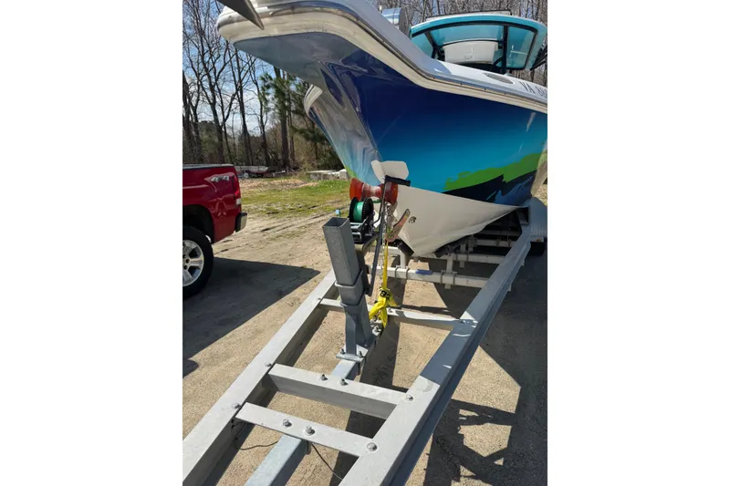 Slide: The Image of 1998 Donzi 30 ZF Daytona boat on trailer, vibrant hull design, parked outdoors. - 25