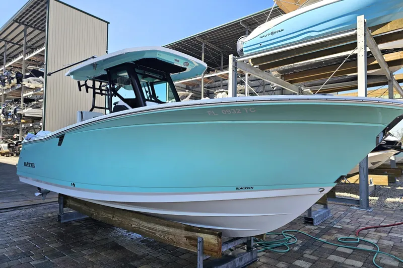 The Image of 2022 Blackfin 272 CC boat in storage, light blue hull, docked on a sunny day. - 0