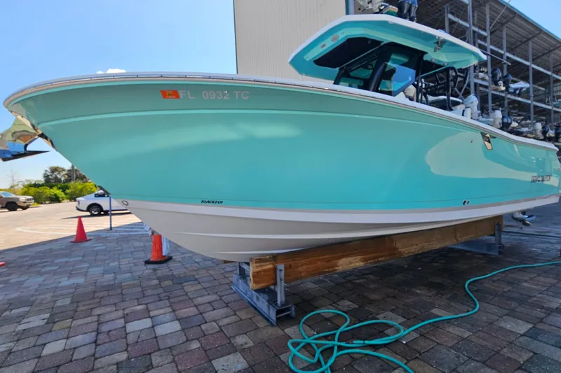 Slide: The Image of 2022 Blackfin 272 CC boat in light blue, displayed on a stand outdoors. - 10